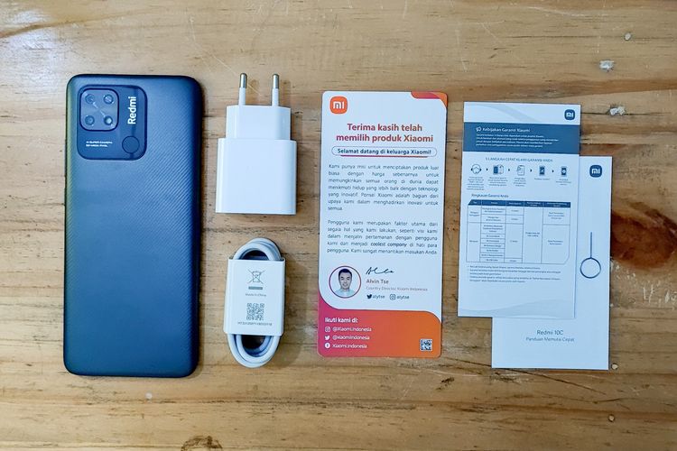 Isi lengkap kotak penjualan Xiaomi Redmi 10C di Indonesia. Ada satu unit ponse, kabel USB type C, adapter charger, SIM card ejector tool, buku panduan penggunaan, kartu garansi, dan surat cinta dari Alvin Tse. Kotak penjualan Redmi 10C tidak dibekali dengan aksesori softcase.