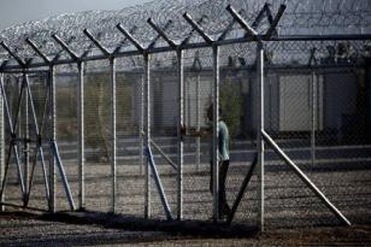 Foto ini diambil pada 30 April 2011 memperlihatkan seorang pengungsi berada di belakang pagar kawat yang membatasi kamp detensi imigrasi Amygdaleza, Athena, Yunani.
