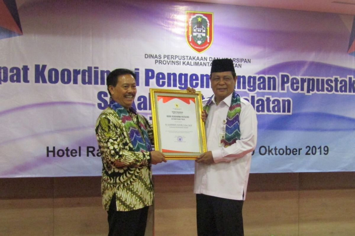 Kepala Perpustakaan Nasional RI Muhammad Syarif Bando memberikan Kepala Perpustakaan Nasional RI Muhammad Syarif Bando memberikan penghargaan Nugra Jasadarma Pustaloka kepada Gubernur Kalimantan Selatan H Sahbirin Noor di Hotel Rattan Inn Banjarmasin, Rabu (9/10).
 kepada Gubernur Kalimantan Selatan, Sahbirin Noor di Hotel Rattan Inn Banjarmasin, Rabu (9/10/2019).
