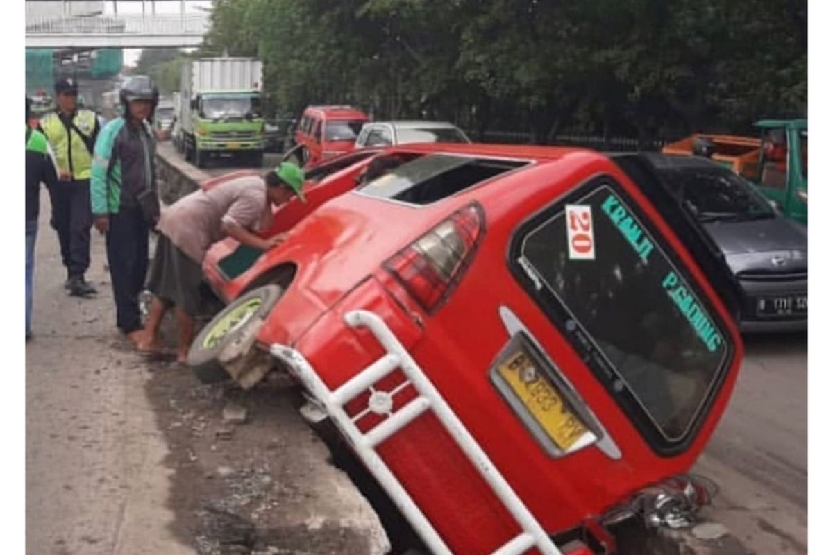 Mobil angkuta perkotaan terperosok ke saluran air di Jalan Raya Bekasi, Cakung, Jakarta Timur, Selasa (21/1/2020).