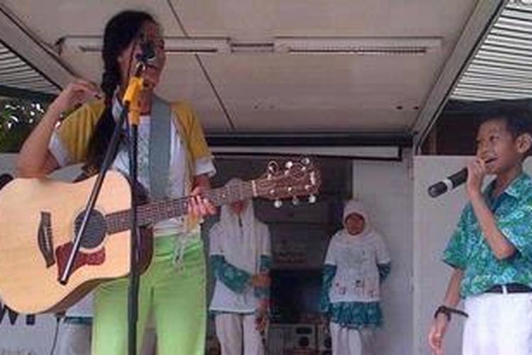 Salah satu siswa SD Lazuardi, Depok, Raihan, menemani penyanyi Oppie Andaresta dalam menyanyikan lagu rap berjudul 3R dalam rangkaian Tur Edukasi Bumiku Lestari, Rabu (14/11/2012).