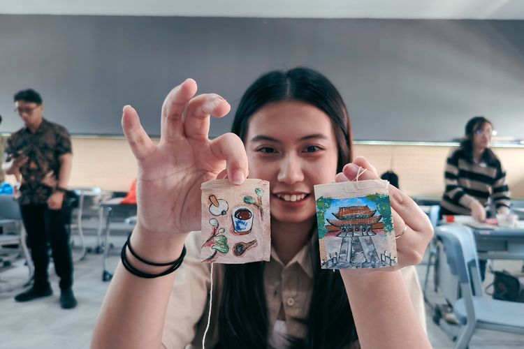 Liona, salah satu Mahasiswa Ubaya menunjukkan hasil karya lukisnya yang menggunakan media kantong teh bekas untuk memperingati hari teh sedunia yang jatuh setiap tanggal 21 Mei.