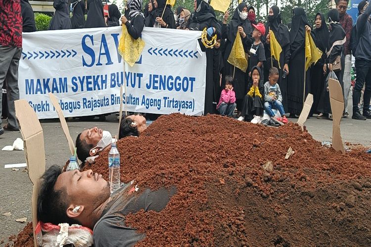 Sejumlah demonstran melakukan aksi kubur diri sebagai bentuk menolak relokasi makam Syekh Buyut Jenggot atau Syekh Tubagus Rajasuta bin Sultan Ageng Tirtayasa di depan gedung Balaikota Tangerang, Kamis (29/9/2022). Warga menuntut wali kota Tangerang untuk segera mengeluarkan pernyataan sikap tegas terkait penolakan relokasi makam ini.