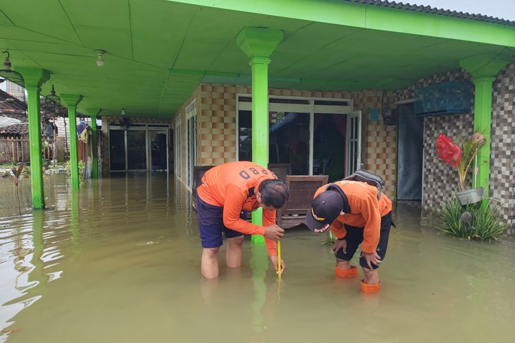 Ket. Foto: Petugas BPBD Sumenep mengukur ketinggian air di wilayah terdampak banjir