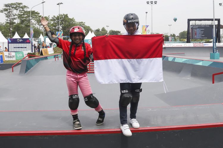 Skateboarder putri Indonesia Aliqqa Novvery (kiri) dan Bunga Nyimas (kanan) mengibarkan bendera merah putih usai mengikuti final skateboard kelas taman putri Asian Games 2018 di arena roller sport Jakabaring Sport City, Palembang, Sumatera Selatan, Rabu (29/8/2018).