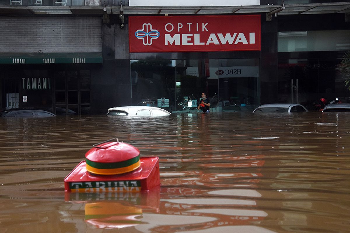 Warga berjalan melewati banjir di kawasan Kemang, Jakarta Selatan, Sabtu (20/2/2021). Banjir yang terjadi akibat curah hujan tinggi serta drainase yang buruk membuat kawasan Kemang banjir setinggi 1,5 meter.