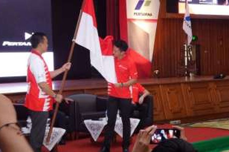 Rio Haryanto mencium bendera Merah Putih yang dipegang Menpora Imam Nahrawi di Gedung Pusat Pertamina, Jakarta, Kamis (18/2/2016).