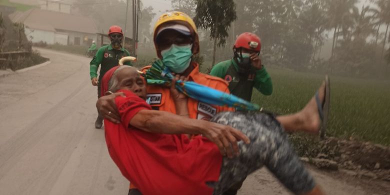 
Seorang petugas terlihat tengah mengevakuasi warga saat erupsi Gunung Semeru, Minggu (4/12/2022).