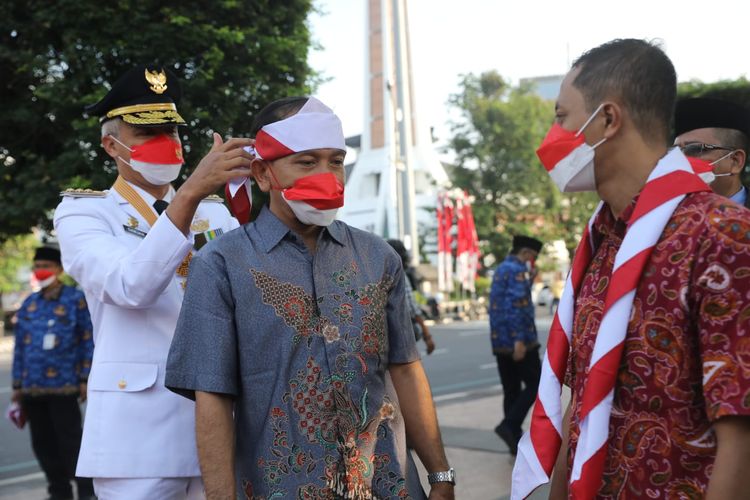 DGubernur Jawa Tengah (Jateng)  Ganjar Pranowo menyematkan hasduk merah putih di kepala Joko Priyono, seorang eks nara pidana teroris (napiter) dalam upacara bendera Hari Ulang Tahun (HUT) ke-77 Republik Indonesia (RI) di Lapangan Pancasila Kota Semarang, Rabu (17/8/2022).
