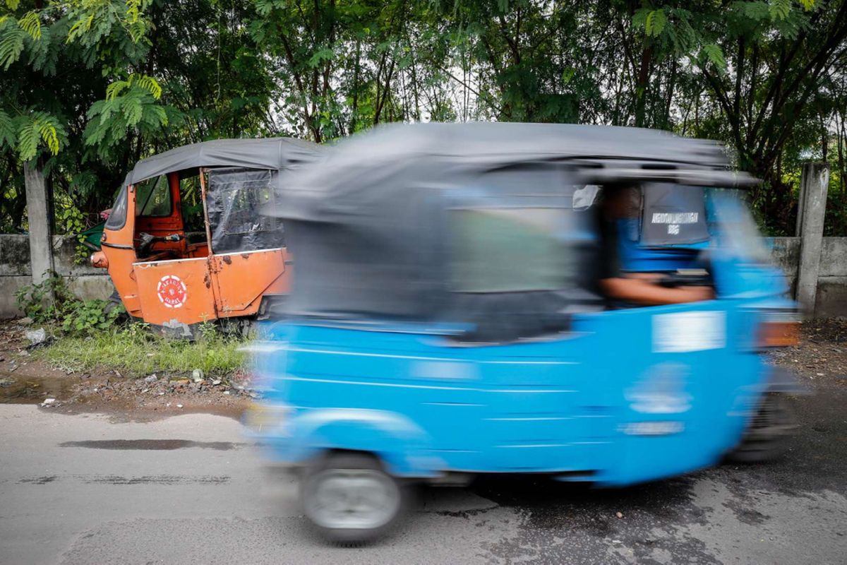 Bajaj biru berbahan bakar gas atau BBG melintasi deretan Bajaj oranye di kawasan Cideng, Jakarta, Senin (5/3/2018). Bajaj oranye yang masuk ke Jakarta pada tahun 1975 dan kini menjadi bangkai bajaj itu dijual seharga Rp5 juta kepada para pelaku bisnis rumah makan untuk digunakan sebagai hiasan di restoran dan cafe.