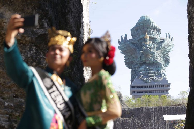 Sejumlah pengunjung berswafoto dengan latar belakang Patung Garuda Wisnu Kencana (GWK) usai diresmikan di Kuta Selatan, Bali, Sabtu (22/09/2018). Patung setinggi 121 meter dengan lebar 64 meter tersebut resmi diresmikan dan menjadi patung tertinggi ketiga di dunia.