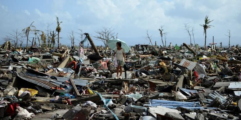 Seorang perempuan terlihat berjalan di antara puing, Senin (11/11/2013). Inilah yang tersisa dari Tacloban, ibu kota provinsi Leyte, Filipina, setelah dihantam super topan Haiyan, Jumat (8/11/2013).