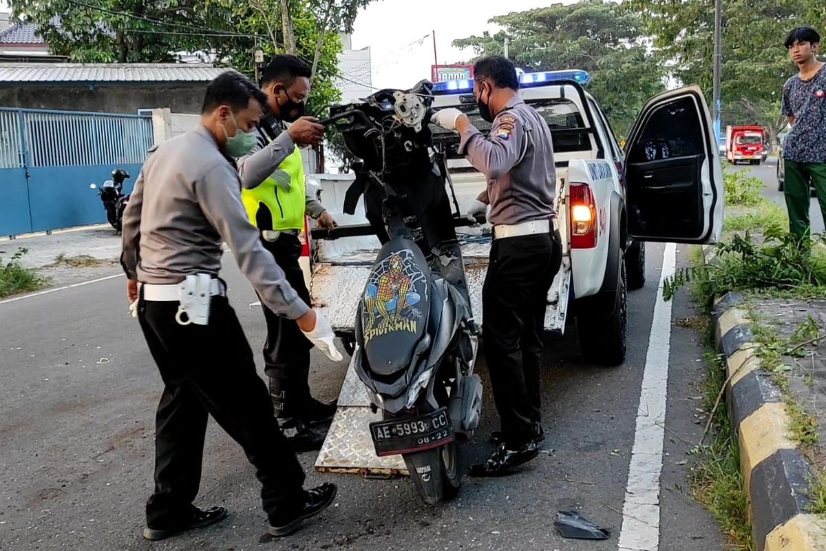 ANGKAT--Anggota Satlantas Polres Madiun Kota mengangkat sepeda motor yang dikendarai RRS usai mengalami kecelakaan lalu lintas di ruas jalan ringroad barat, Kota Madiun, Jawa Timur, Rabu (11/5/2022) sore. 