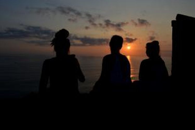 Tiga wisatawan mancanegara asal Jerman duduk untuk menikmati matahari terbenam di salah satu pelataran obyek wisata Uluwatu, Desa Pecatu, Kecamatan Kuta Selatan, Kabupaten Badung, Bali, Selasa (17/11/2015). 