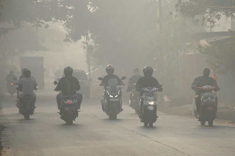 Sejumlah pengendara melintas menembus asap akibat kebakaran di Tempat Pembuangan Akhir (TPA) Antang Makassar, Sulawesi Selatan, Rabu (18/9/2019). Kebakaran sampah di TPA Antang yang terjadi sejak Minggu (15/9/2019)  tersebut mengakibatkan sebagian daerah di Makassar dan Kabupaten Gowa diselimuti asap pada pagi hari yang dapat mengganggu kesehatan pernapasan.