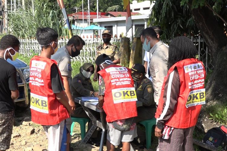 Beberapa warga Kota Jayapura yang terjaring razia masker tengah menjalani hukuman sosial dengan membersihkan fasilitas umum menggunakan rompi berlabel OKB atau orang kepala batu, Jayapura, Papua, Selasa (23/6/2020)