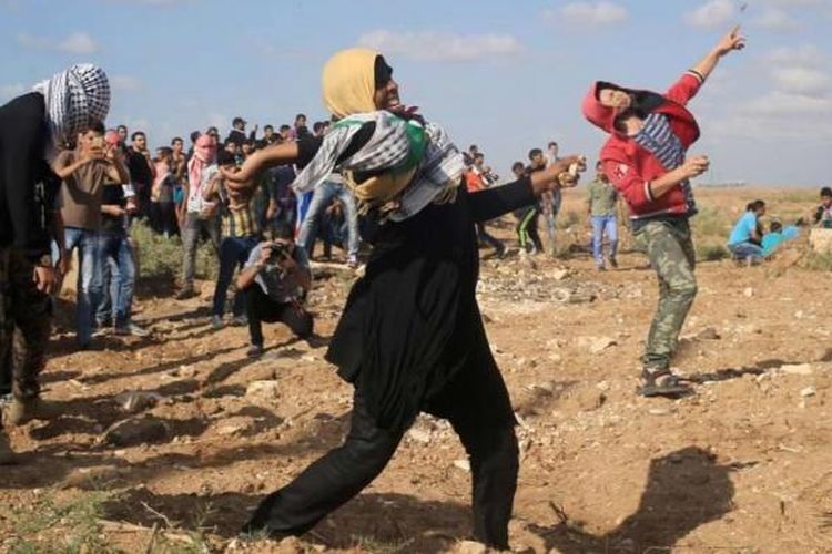 Perempuan Palestina bersama warga melempar batu ke arah tentara Israel dalam bentrokan yang terjadi di Jalur Gaza, 9 Oktober 2015.
