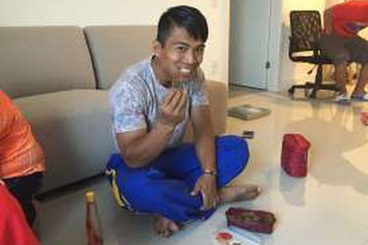 Lifter Indonesia, Deni, menikmati daging yang dia sebut camilan saat berada di athlete village Olimpiade Rio 2016, Selasa (9/8/2016).