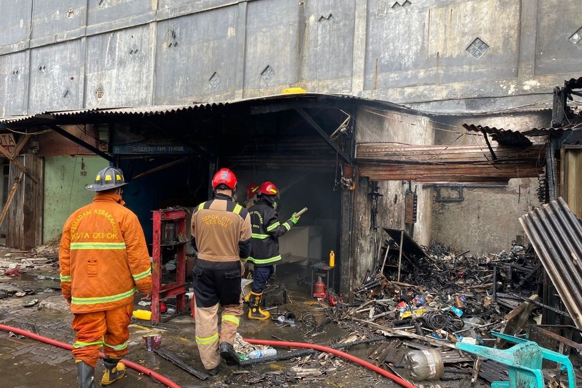 Petugas pemadam kebakaran tengah melakukan pendinginan di area bengkel dan toko sparepart mobil di Jalan Margonda Raya, Depok, yang terbakar, pada Rabu (10/5/2023).