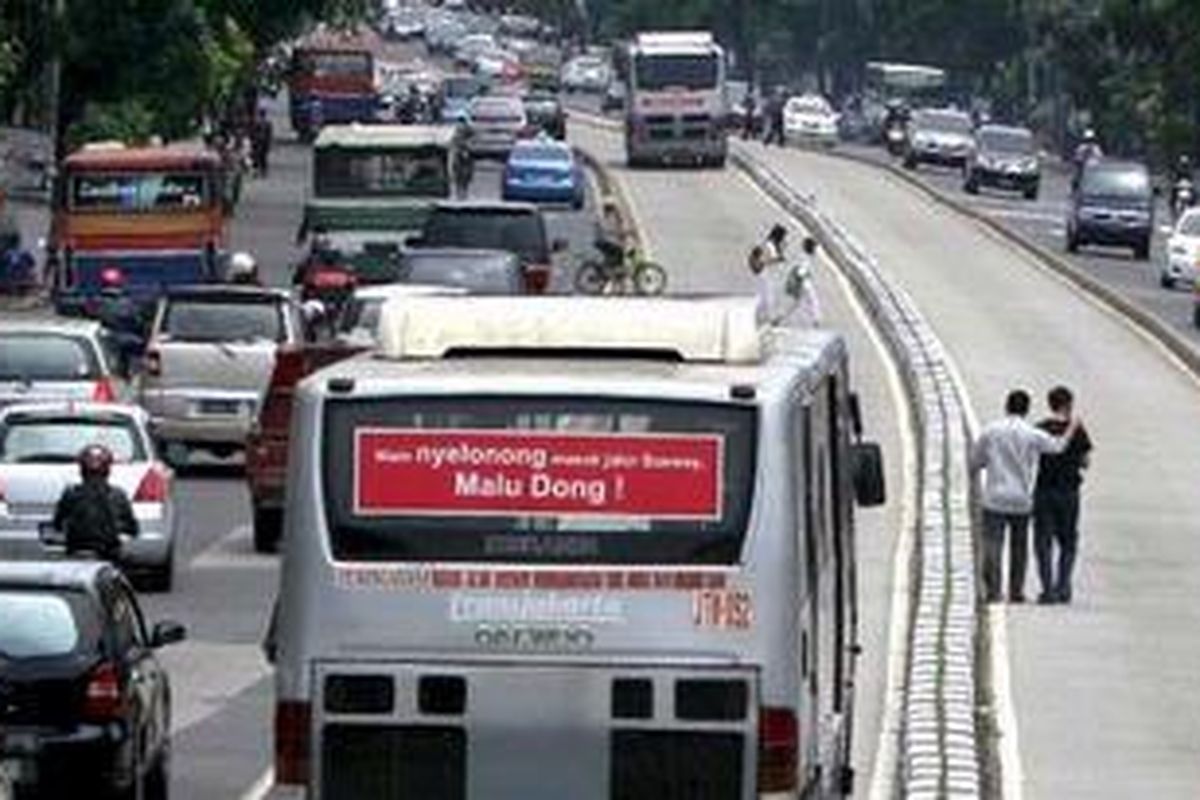 Warga lalu lalang melintas di jalur bus Transjakarta di kawasan Mampang Prapatan, Jakarta, Senin (21/3/2011). Selain tidak adanya pagar pembatas, jembatan penyeberangan yang berjauhan membuat warga memilih menyeberang di tengah jalan.