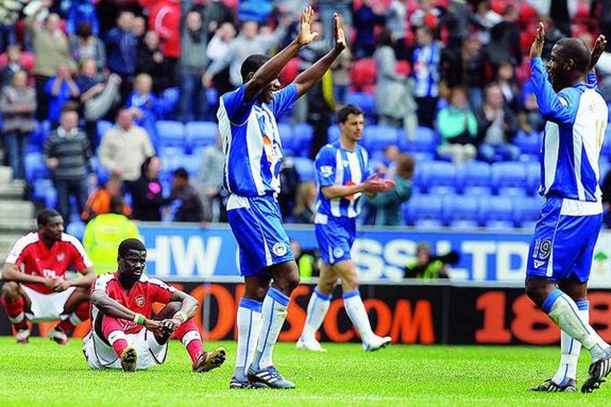 Pemain Arsenal, Emmanuel Eboue (kedua dari kanan), terduduk menyaksikan pemain Wigan Athletic merayakan kemenangan mereka pada laga Liga Inggris di Stadion DW, Wigan, Inggris, Minggu (18/4). Arsenal takluk 2-3.