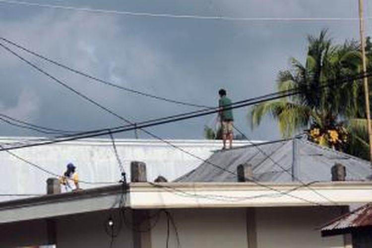 Warga di Ranoketang Atas, Kecamatan Touluaan, Kabupaten Minahasa Tenggara membersihkan atap rumah mereka yang terkena dampak abu vulkanis letusan Gunung Soputan yang meletus 6 Januari 2015.