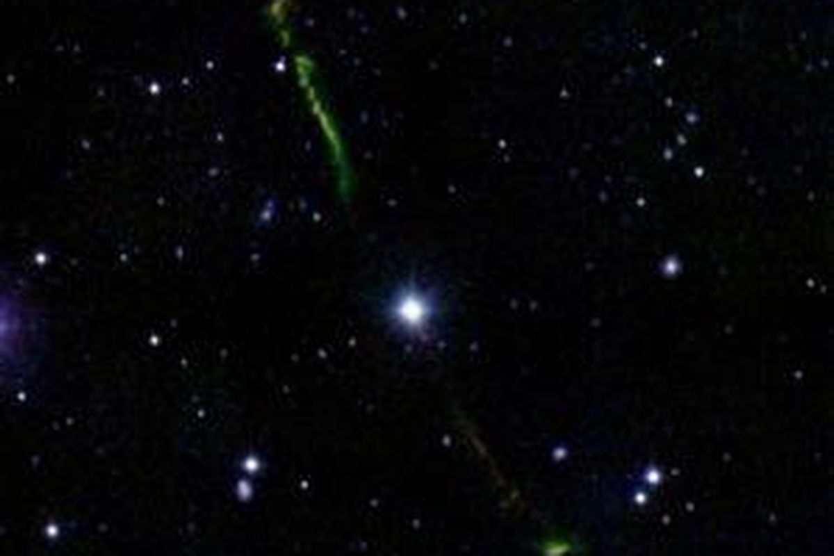 Debu dan gas pembentuk formasi planet (semburat hijau dan merah) terbentuk di sekitar bintang tua BP Piscium (tengah) di konstelasi Pisces.