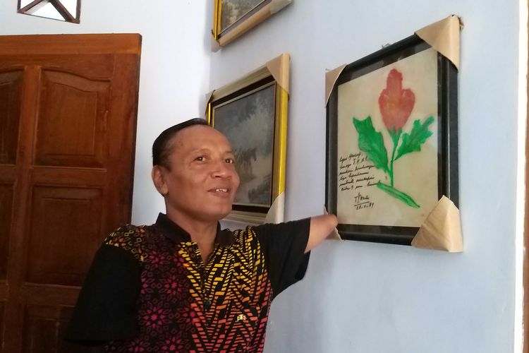 Agus Yusuf, pelukis difabel asal Desa Sidomulyo, Kecamatan Sawahan, Kabupaten Madiun yang melukis menggunakan mulut dan kakinya menunjukan karyanya yang ditandatangani ibu negara, Ibu Tien Suharto .