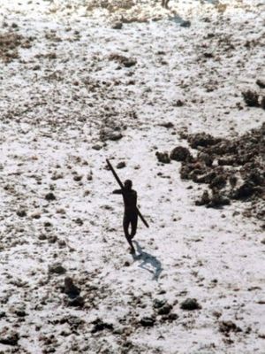 Foto ini diambil 28 Desember 2004 menunjukkan seorang pria suku Sentinel mengarahkan busur dan anak panahnya ke sebuah helikopter Pasukan Penjaga Pantai India saat terbang melintasi Pulau Sentinel Utara di Kepulauan Andaman. (AFP)
