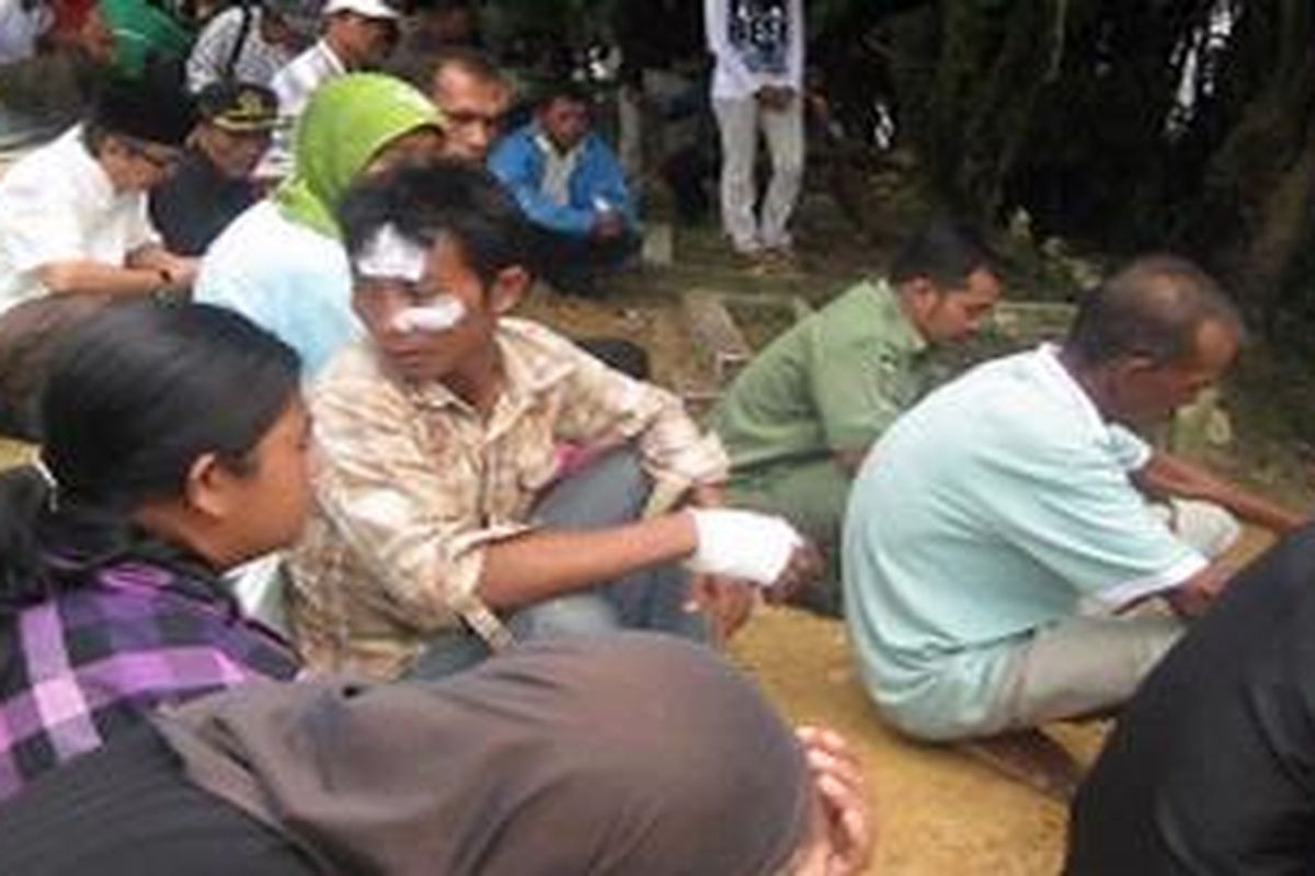 Putra Abdullah dengan luka di wajah dan tangan tampak menghadiri pemakaman ayahnya bersama ratusan warga lainnya, Senin (27/9/2010).