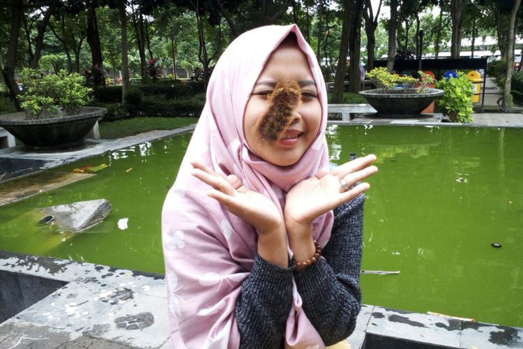Eli Yulianti (23), gadis asal Medowo, Kabupaten Kediri, Jawa Timur, bermain ulat bulu di wajahnya.