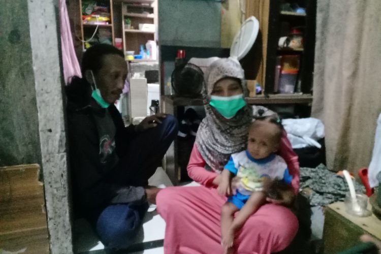 Laila Fitriyah duduk dipangkuan kedua orangtuanya, Surahman (41) dan Yuliani (34) di rumahnya seluas 3x3 meter di Jalan Tanjung Sari, Jaya Bakti, Kecamatan Tandes, Surabaya, Rabu (2/2/2022) malam.