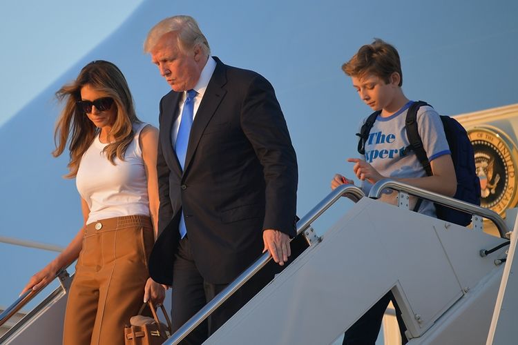 Presiden AS Donald Trump menuruni tangga Air Force One bersama istrinya Melania dan putranya, Barron di pangkalan udara Andrews, Maryland.