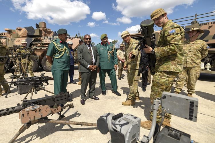 Foto yang diambil pada 20 Februari 2025 dan dirilis oleh Angkatan Pertahanan Australia ini menunjukkan Menteri Pertahanan Papua Nugini Billy Joseph (kedua dari kiri) dan para pejabat berbicara dengan tentara Resimen Kerajaan Australia dari Resimen ke-8/9.