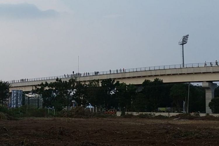 Para penumpang LRT Palembang berjalan diatas rel menuju ke stasiun Jakabaring, karena kereta mendadak mogok, Minggu (12/8/2018)