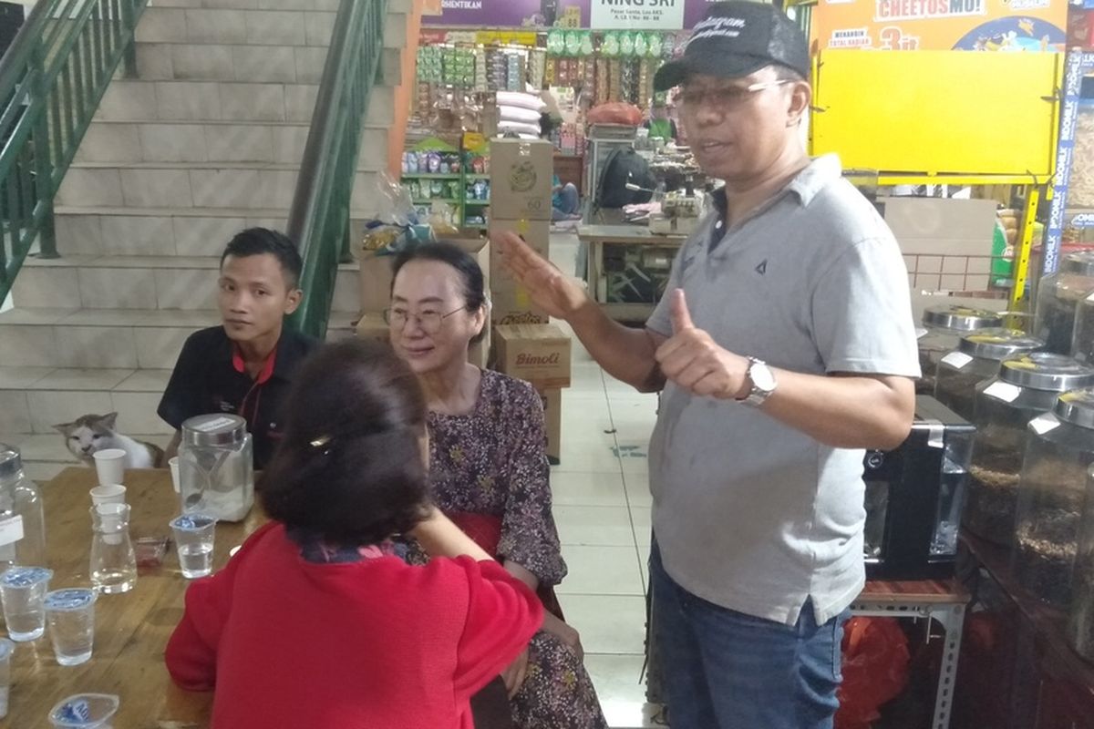 Suradi selaku pemilik kedai Dunia Kopi di Pasar Santa sedang berbicara dengan pelanggannya asal Korea Selatan, Jakarta Selatan, Senin (16/12/2019)