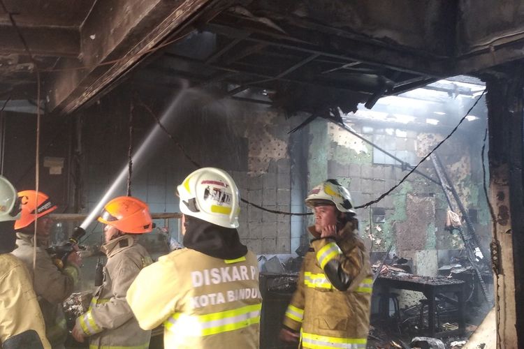 Sejumlah petugas pemadam kebakaran dari Diskar PB Kota Bandung sedang berupaya memadamkan kobaran api yang melahap ruko di depan Pasar Simpang Dago, Jalan Ir. H Juanda, Kota Bandung, Jawa Barat, Jumat (26/7/2024).