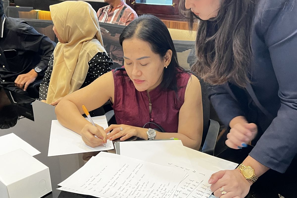 Agen properti PT Bamboosea Properti, Desi Nuryanti, saat menuliskan surat perjanjian kesepakatan pengembalian uang ganti rugi dalam mediasi di Kantor Pemkot Surabaya, Kamis (26/6/2025).