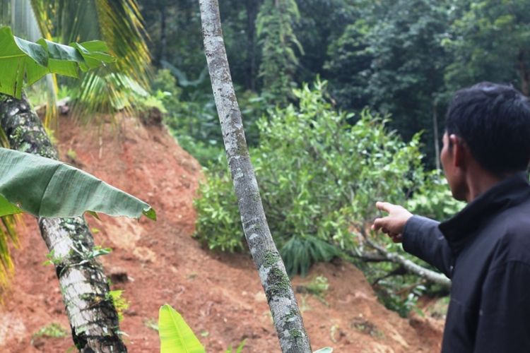 Seorang warga memerlihatkan sisa longsoran di lereng bukit yang menerjang puluhan rumah hingga ambruk, dan belasan lainnya rusak.