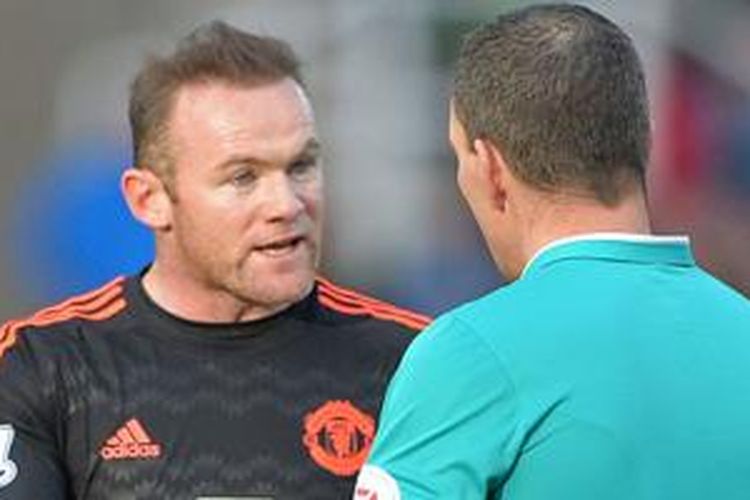 Wayne Rooney berdiskusi dengan wasit Kevin Friend saat Manchester United bertandang ke markas Stoke City, Sabtu (26/12/2015). 