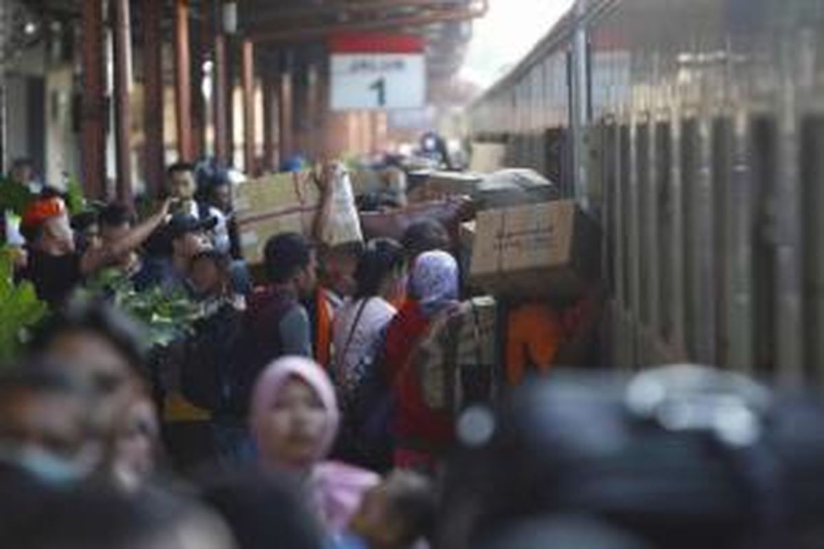 Pemudik masuk ke dalam kereta api di Stasiun Pasar Senen, Jakarta, Senin (13/7/2015).  