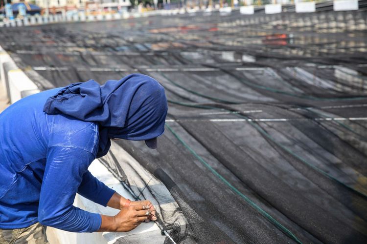 Pekerja memasang jaring-jaring untuk menutupi aliran Kali Sentiong atau Kali Item di Jakarta Utara, Jumat (20/7/2018). Pemasangan jaring-jaring berbahan nilon untuk mengatasi buruknya rupa Kali Item sebelum menerima para atlet Asian Games 2018 dari mancanegara yang akan menginap di Wisma Atlet.