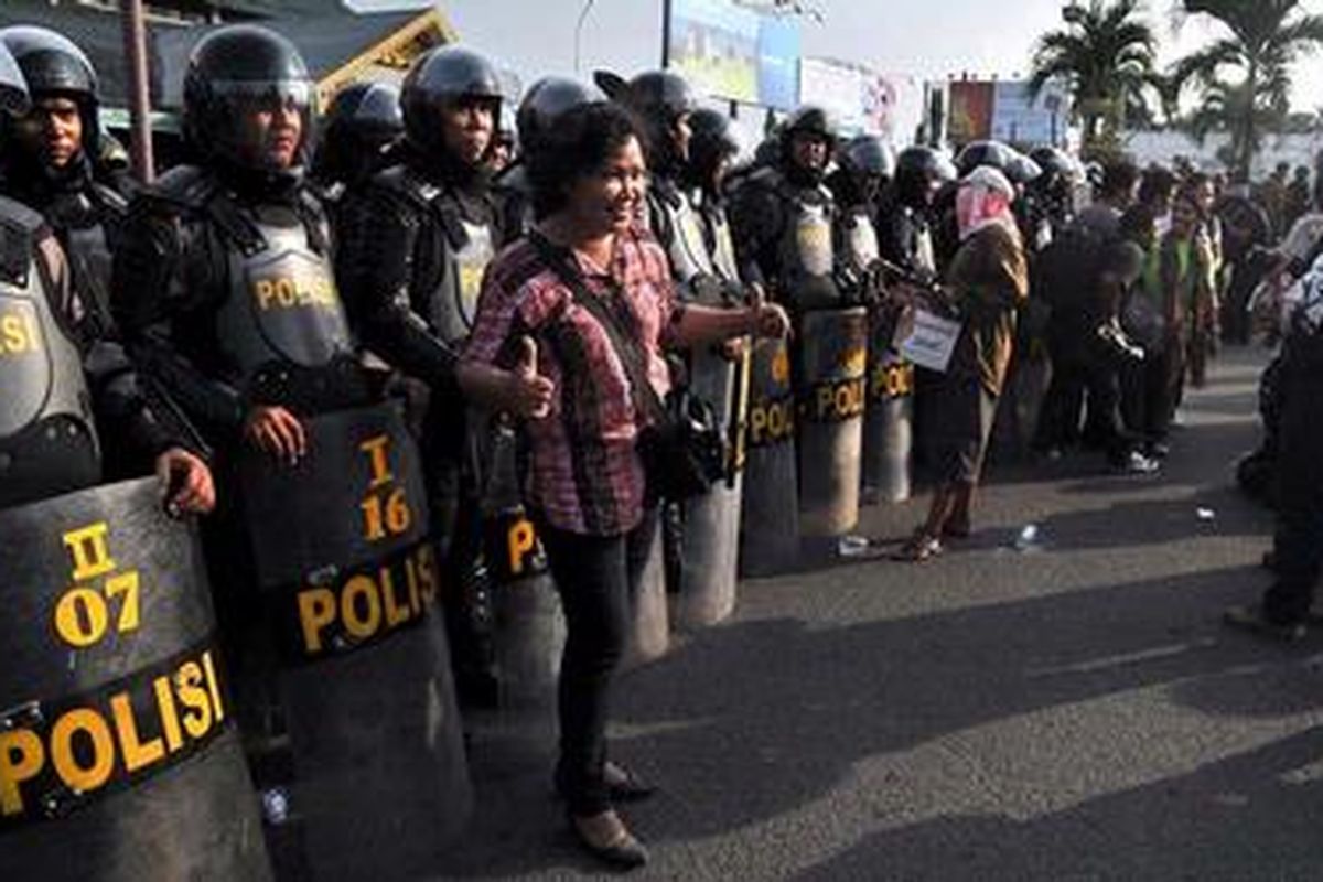 wartawan berpose di depan barisan polisi di Bandara Internasional Polonia Medan, Senin (26/3/2012) petang. 
