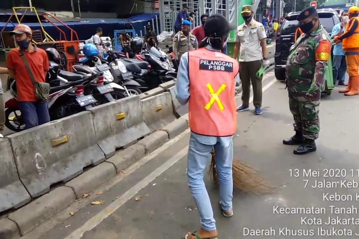 Tangkapan layar video pelanggar PSBB di kawasan Tanah Abang, Jakarta Pusat, menggunakan rompi oranye saat menjalani sanksi kerja sosial.