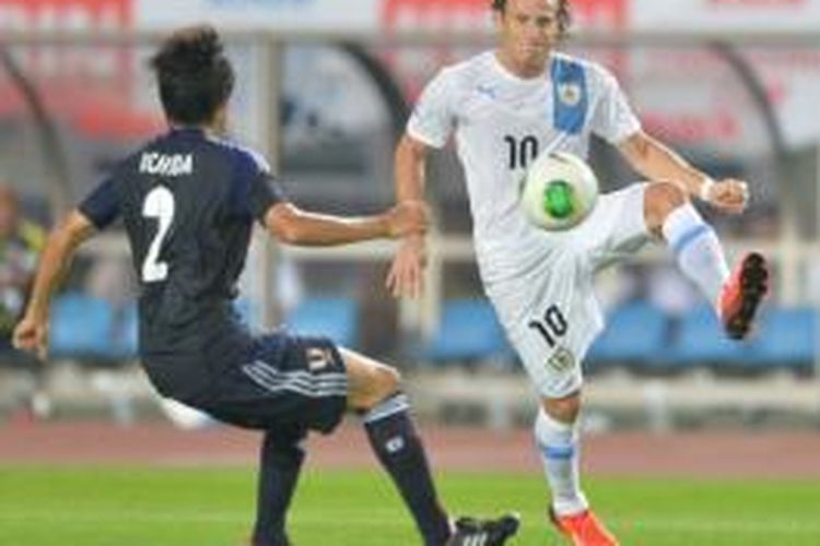 Striker Uruguay, Diego Forlan (kanan), mendapat pengawalan dari bek Jepang, Atsuto Uchida (kiri), pada laga di Stadion Miyagi, Rifu, Rabu (14/8/2013). Forlan mencetak dua gol untuk membawa Uruguay menang 4-2 atas Jepang.