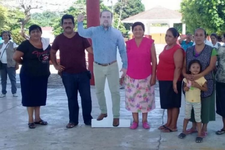 Pegawai layanan kesehatan di Pichuclaco, Meksiko, berfoto dengan foto Wali Kota Moises Aguilar Torres. Sang wali kota menuai kecaman karena hanya memajang foto dirinya ketika berhalangan hadir dalam suatu acara.