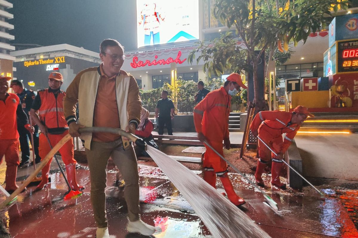 Walikota Jakpus Dhany Sukma membantu menyemprotkan air saat bersih-bersih trotoar di kawasan Jalan MH Thamrin, Menteng, Jakarta Pusat, Selasa (22/8/2023) malam. (KOMPAS.com/XENA OLIVIA)