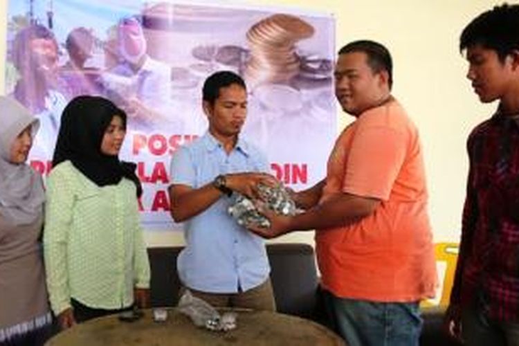 Mahasiswa korban Tsunami di Aceh Barat menyerahkan koin untuk mengembalikan bantuan Australia melalui Pengurus KAMMI Aceh selaku penggagas penggelangan koin, Senin (2/3/2015).