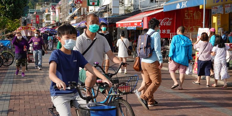 Warga Hong Kong terlihat memakai masker bepergian di pulau Cheung Chau saat libur Paskah, di tengah merebaknya virus corona. Foto diambil pada 12 April 2020.
