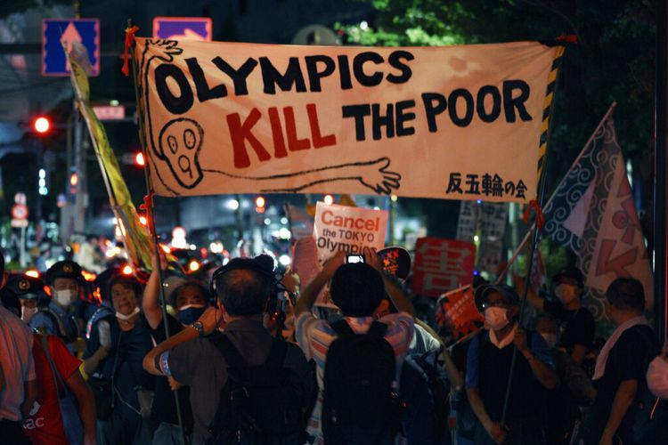 Para pengunjuk rasa anti-Olimpiade berdemonstrasi di dekat Stadion Nasional di Tokyo, Jepang di mana upacara pembukaan Olimpiade Tokyo berlangsung, Jumat, 23 Juli 2021. 